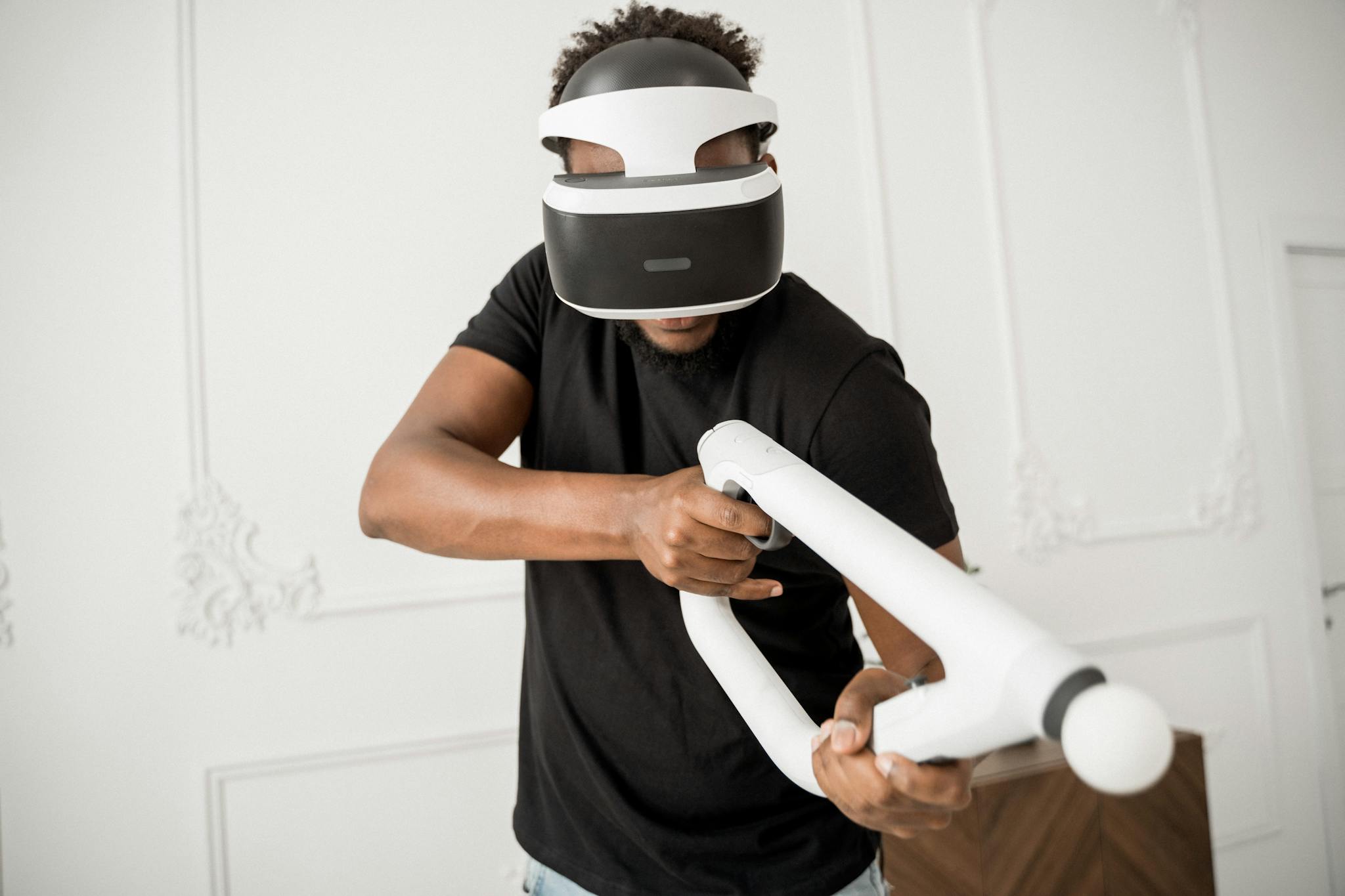 A man wearing VR glasses actively engaged in a virtual reality gaming experience indoors.