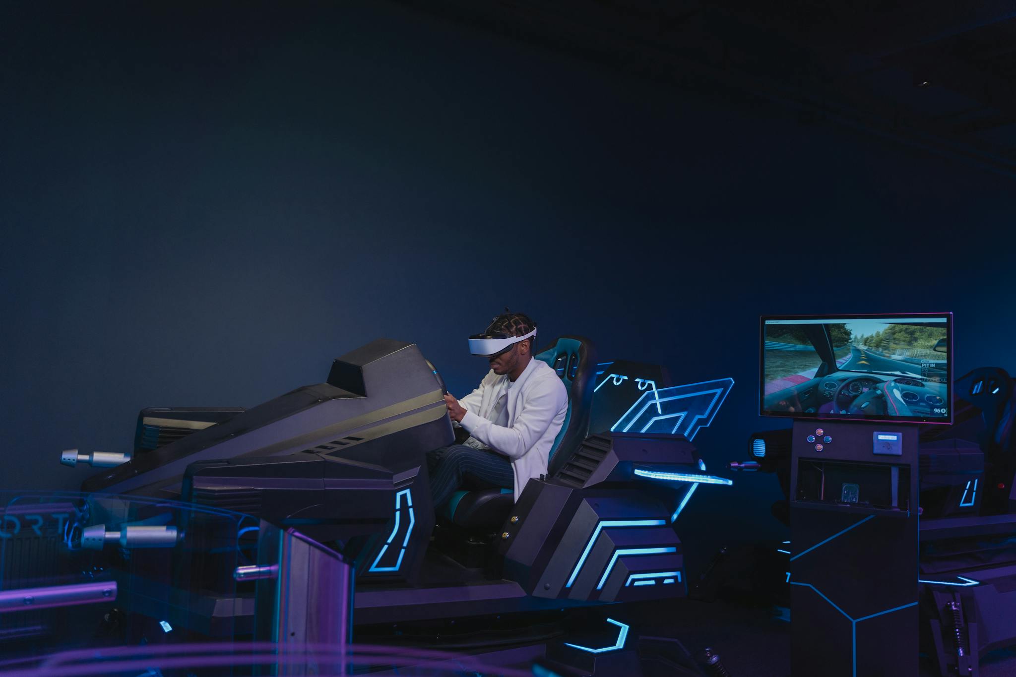 A young man immersed in a virtual reality driving simulation, wearing a VR headset indoors.
